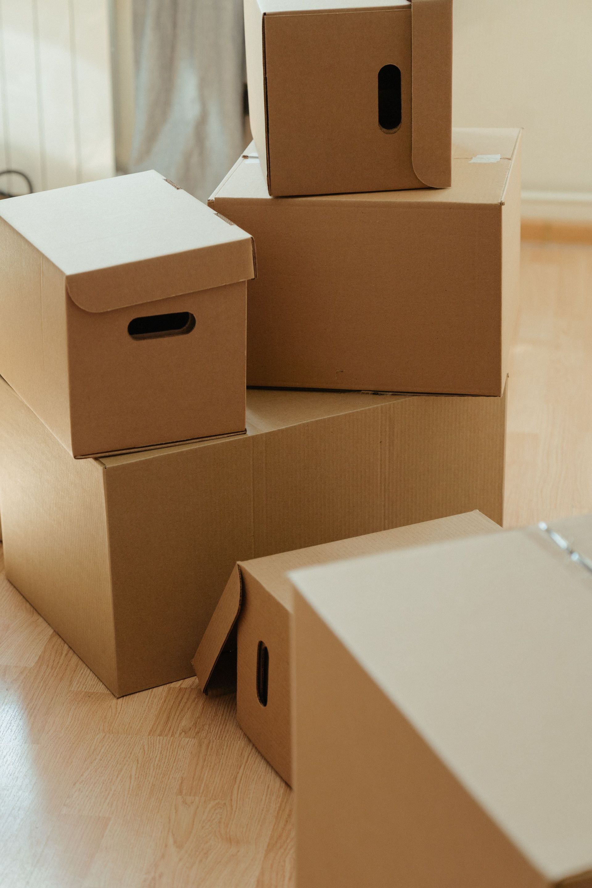 Cardboard boxes stacked on a wooden floor, symbolizing moving and new beginnings.